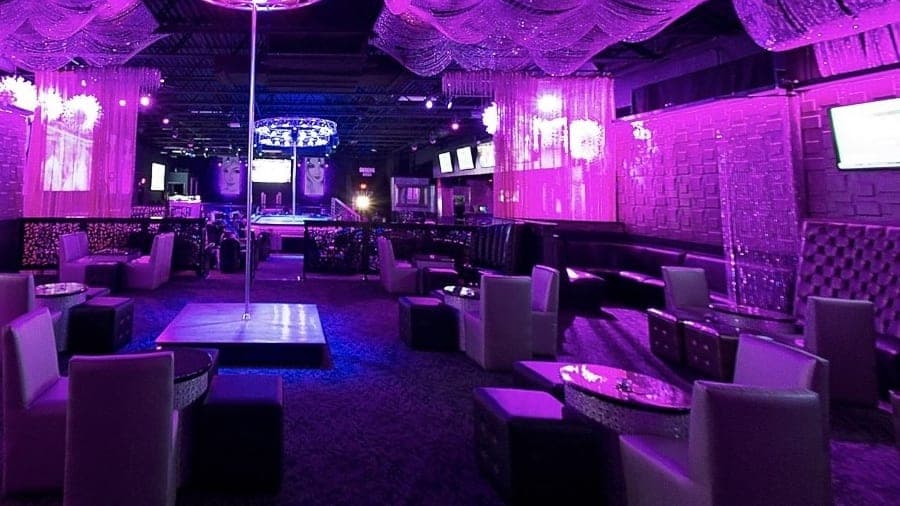 White armchairs and small tables around a stage in the private VIP room