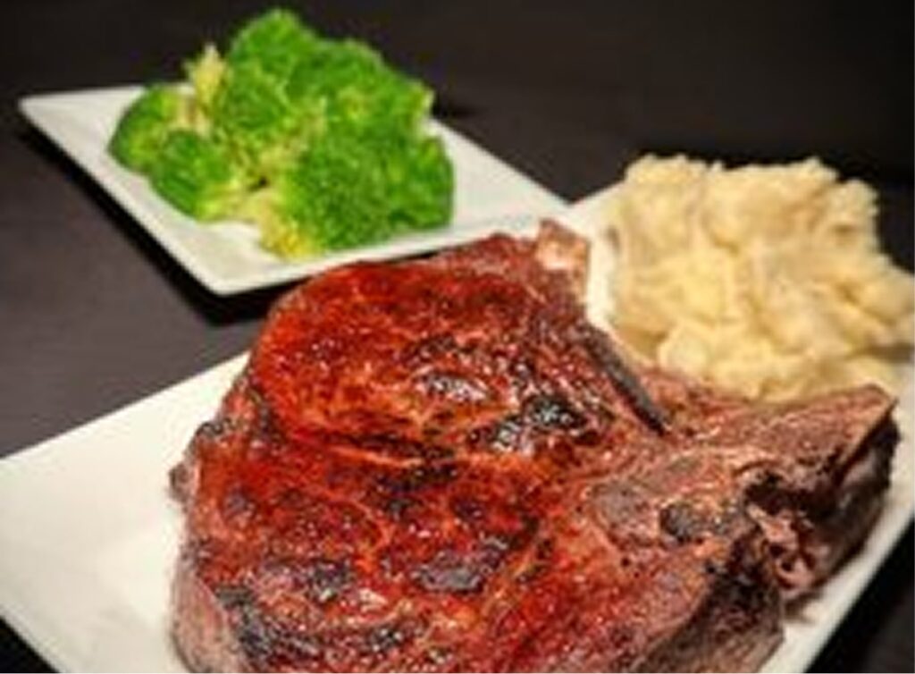 An image of a juicy grilled steak served with mashed potatoes and fresh greens.