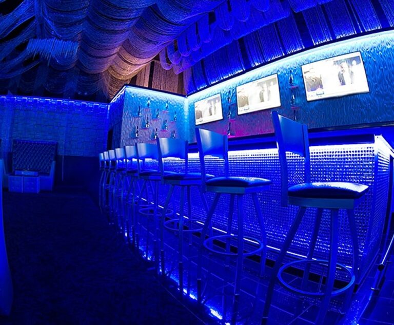 Modern bar area with illuminated seating and multiple TV screens in Chicago.