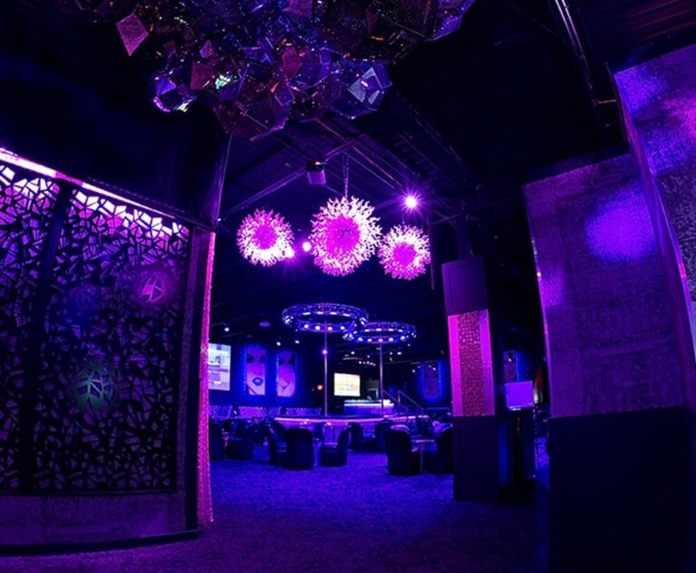 Modern bar area with illuminated seating and multiple TV screens in Chicago.